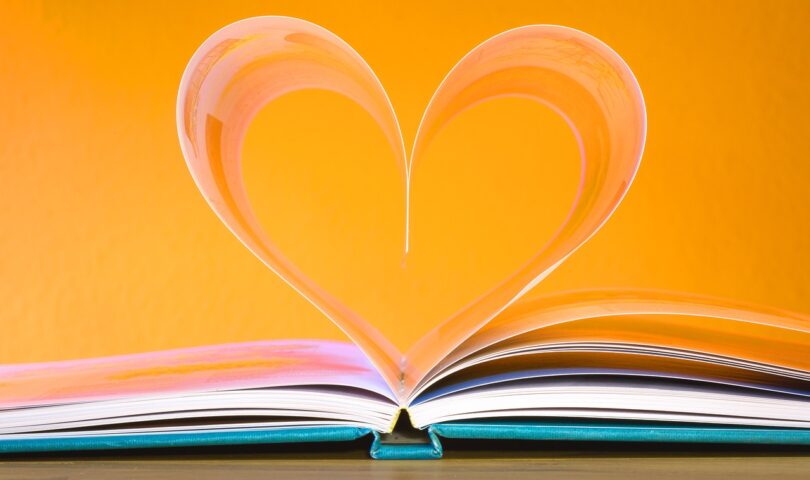 decorative photo of a book whose pages form a heart on an orange background